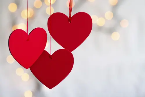 Image "Three red hearts suspended by strings against a background of soft light, creating a festive atmosphere" (3504x2336)