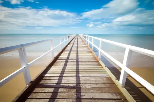 Image "A long wooden pier extending into the sea under a blue sky with clouds" (5472x3648)